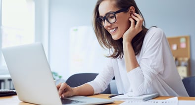 Women with glasses on her laptop smiling