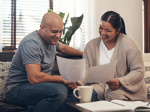 A happy couple comparing two paper document in their living room