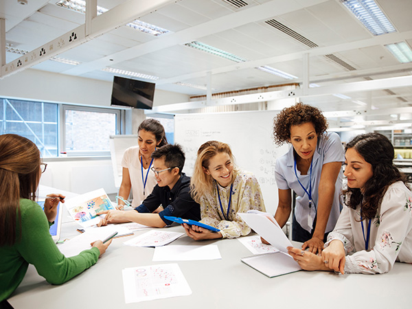 group of people around a work table discussing ideas with documents in hand